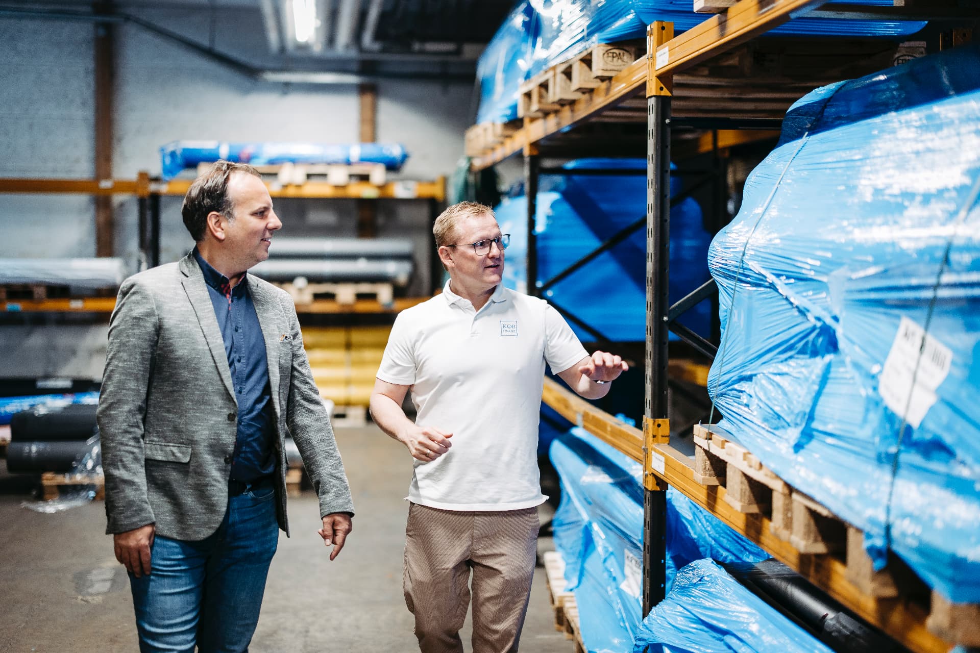 Jochen Köb von KOEB Finanz geht mit einem Unternehmer durch das Lager seines Betriebs